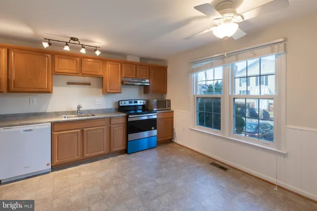 a kitchen with stainless steel appliances granite countertop a stove a sink dishwasher a refrigerator and a dining table with wooden floor