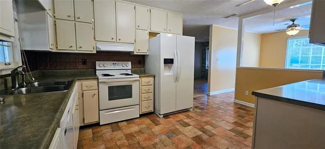 a kitchen with stainless steel appliances granite countertop a refrigerator a stove and a sink