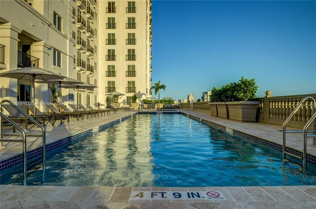 a view of a swimming pool with chairs and umbrellas