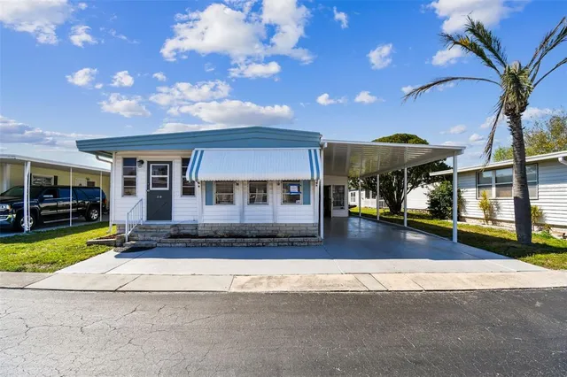 a front view of a house with a yard outdoor seating and covered with large trees