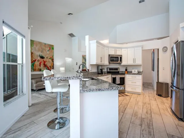 a kitchen with stainless steel appliances granite countertop a refrigerator oven a sink dishwasher and white cabinets with wooden floor