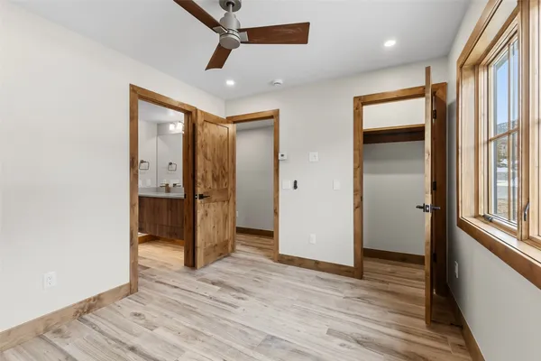 a view of a hallway with wooden floor and a bathroom