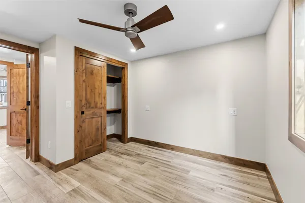 an empty room with wooden floor cabinet and windows