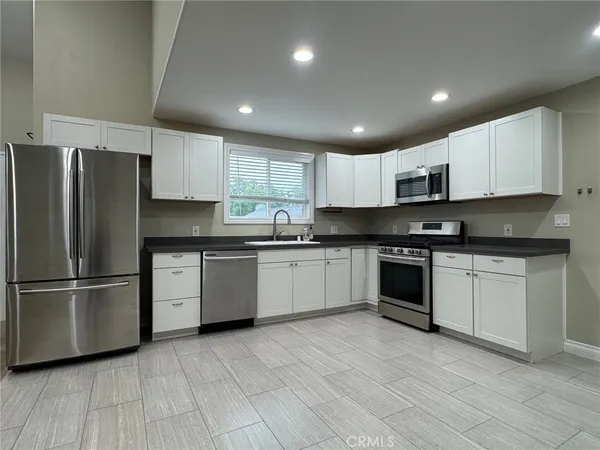 a kitchen with stainless steel appliances granite countertop a refrigerator sink and white cabinets