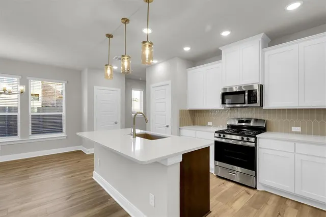 a kitchen with a sink stove and wooden floor