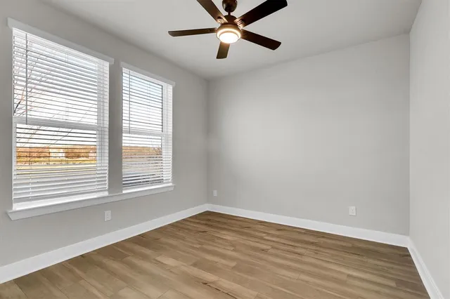 a view of empty room with wooden floor and fan