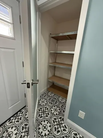 a view of an empty room with window and a kitchen