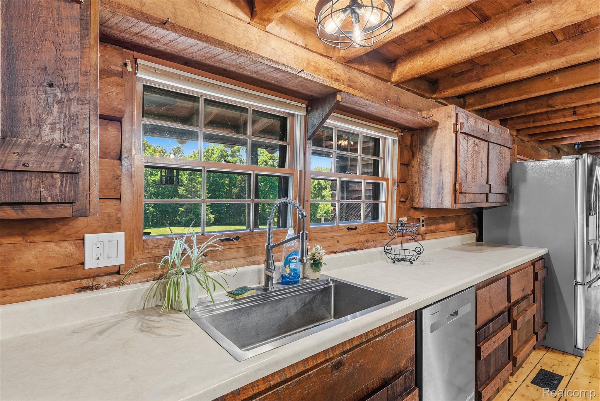 3656 Stanley Road Columbiaville, MI 48421 - Photo 16 of 65 Log cabin kitchen featuring exposed beam ceiling, wood-finish cabinetry, a stainless steel double-basin sink, and a modern pull-down faucet