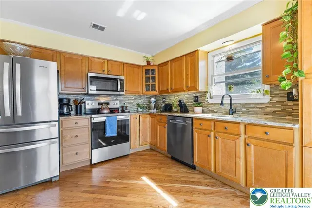 a kitchen with stainless steel appliances granite countertop a refrigerator a stove a sink and a microwave