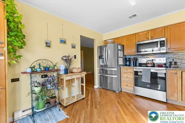 a kitchen with stainless steel appliances a stove a refrigerator and a wooden floor