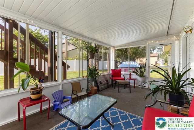 a living room with furniture a flat screen tv and a floor to ceiling window
