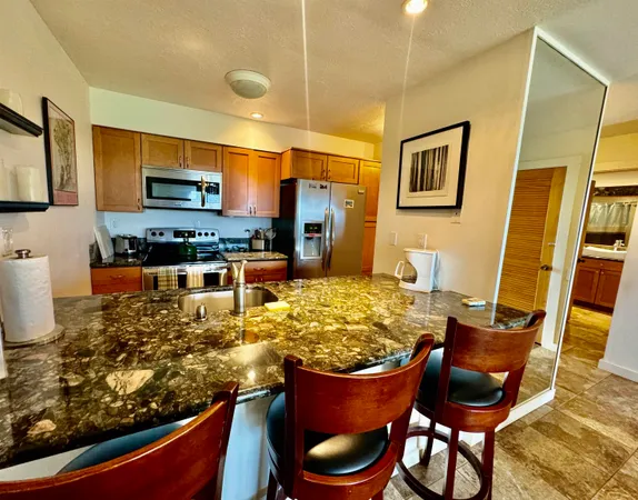 a kitchen with stainless steel appliances granite countertop a stove top oven a sink a dining table and chairs