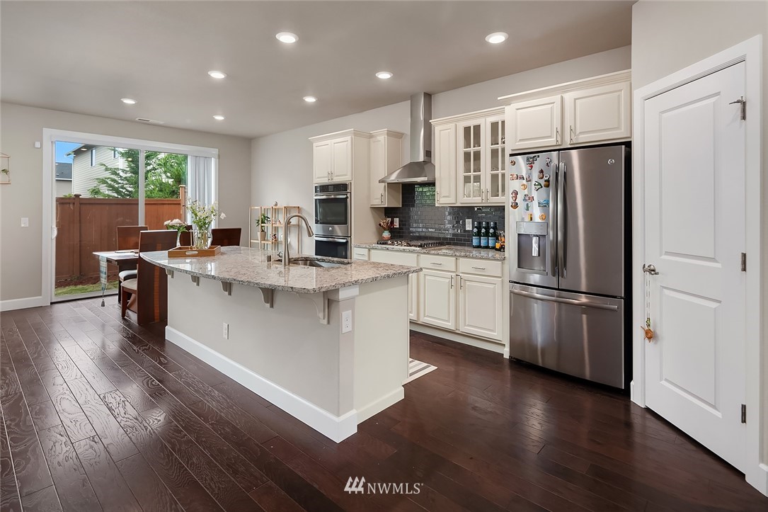 3911 174th Place Southeast Bothell, WA 98012 - Photo 5 of 27 a kitchen with stainless steel appliances granite countertop a refrigerator a sink dishwasher a stove and white cabinets with wooden floor