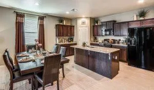 a kitchen with stainless steel appliances kitchen island granite countertop a table chairs and a refrigerator
