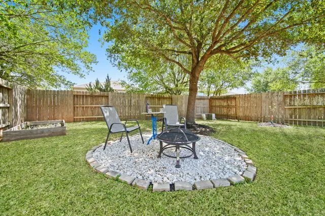 a view of a backyard with table and chairs potted plants and large tree