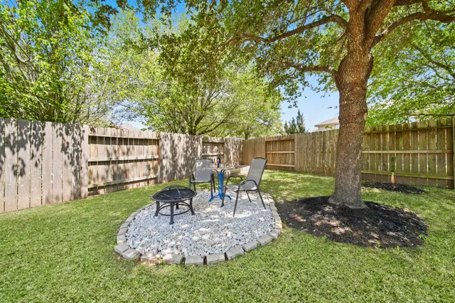 a view of a backyard with wooden fence and a large tree