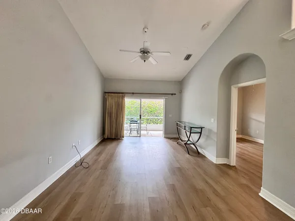 an empty room with wooden floor fan and windows