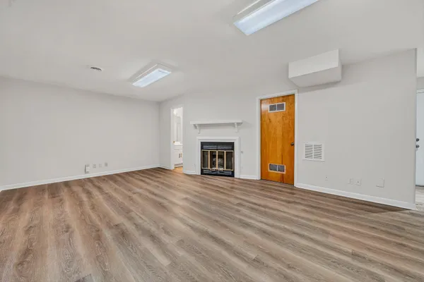 an empty room with wooden floor fireplace and windows