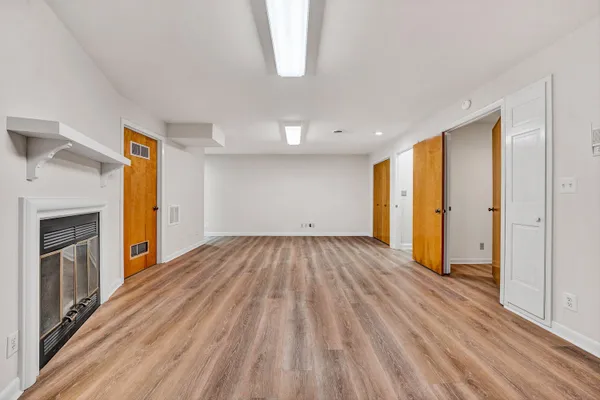 a view of empty room with wooden floor and fireplace
