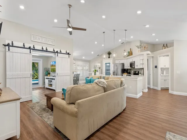 a living room with furniture kitchen area and a wooden floor