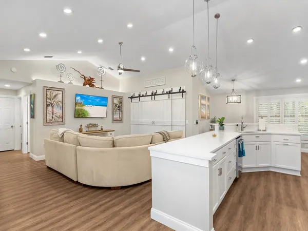 a large white kitchen with a white countertops a stove a sink and a flat screen tv