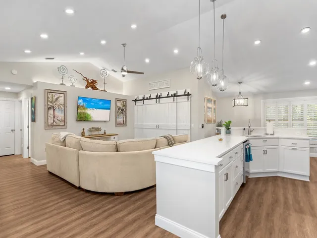 a large white kitchen with a white countertops a stove a sink and a flat screen tv