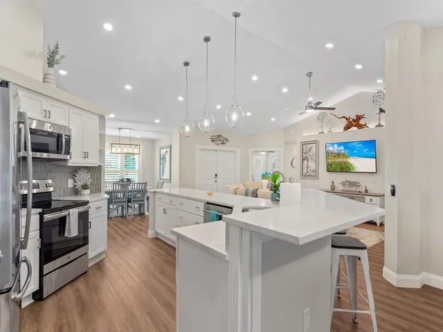 a kitchen with stainless steel appliances kitchen island granite countertop a sink and a refrigerator