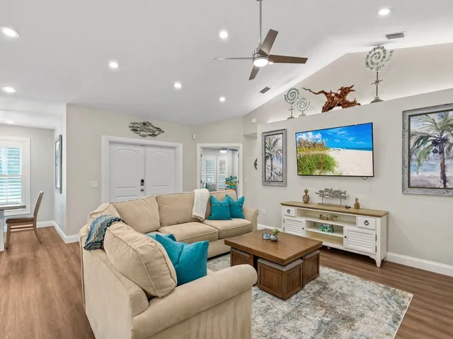 a living room with furniture kitchen view and a wooden floor