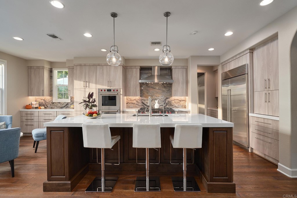 3566 Calle Palmito Carlsbad, CA 92009 - Photo 4 of 40 a kitchen with stainless steel appliances kitchen island granite countertop a dining table chairs and white cabinets
