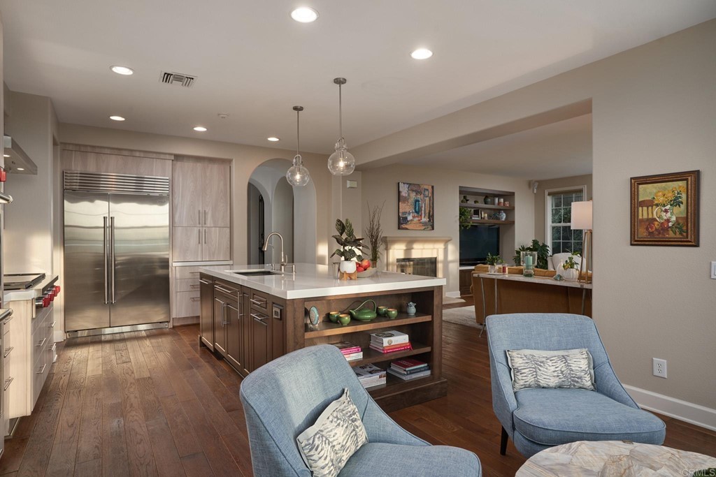 3566 Calle Palmito Carlsbad, CA 92009 - Photo 7 of 40 a large living room with stainless steel appliances granite countertop furniture a fireplace a rug kitchen view and a chandelier