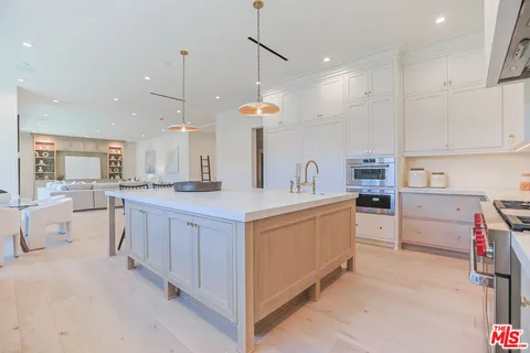 a large white kitchen with lots of counter space a sink a appliances and cabinets