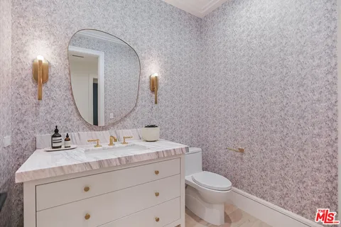 a bathroom with a toilet a sink a vanity and mirror
