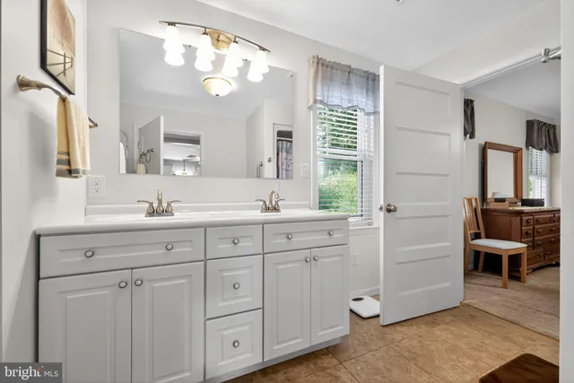 a spacious en suite bathroom with double sink and a mirror