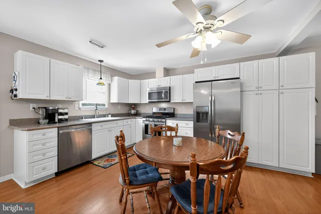 a kitchen with stainless steel appliances granite countertop a dining table chairs refrigerator and cabinets