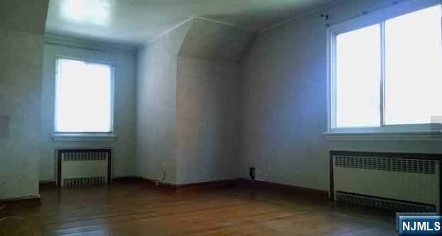 208 Columbus Place, Unit 2 Cliffside Park, NJ 07010 - Photo 2 of 9 a view of an empty room with wooden floor and a window