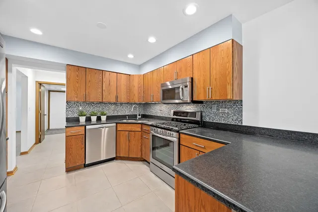 a kitchen with stainless steel appliances granite countertop a stove a sink and a refrigerator