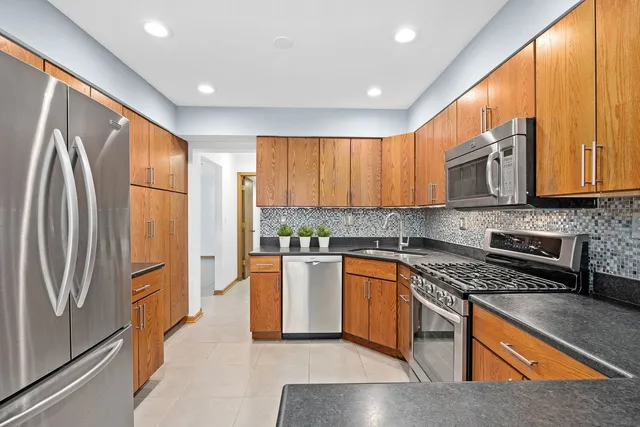 a kitchen with stainless steel appliances granite countertop a refrigerator a stove top oven a sink and dishwasher