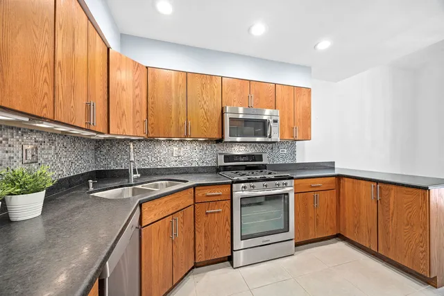 a kitchen with stainless steel appliances granite countertop a sink a stove and a microwave