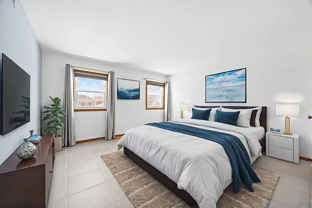 a spacious bedroom with a bed a tv and wooden floor