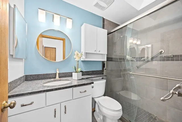 a bathroom with a granite countertop toilet sink and mirror