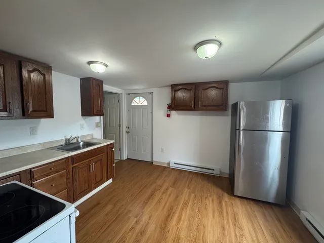 a kitchen with stainless steel appliances granite countertop a refrigerator a sink and wooden floor