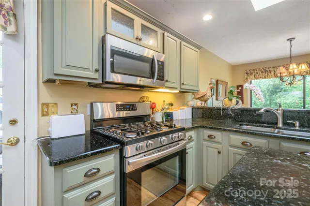 a kitchen with stainless steel appliances granite countertop a stove a sink and a microwave