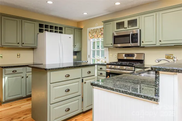 a kitchen with stainless steel appliances granite countertop a stove a sink and a microwave