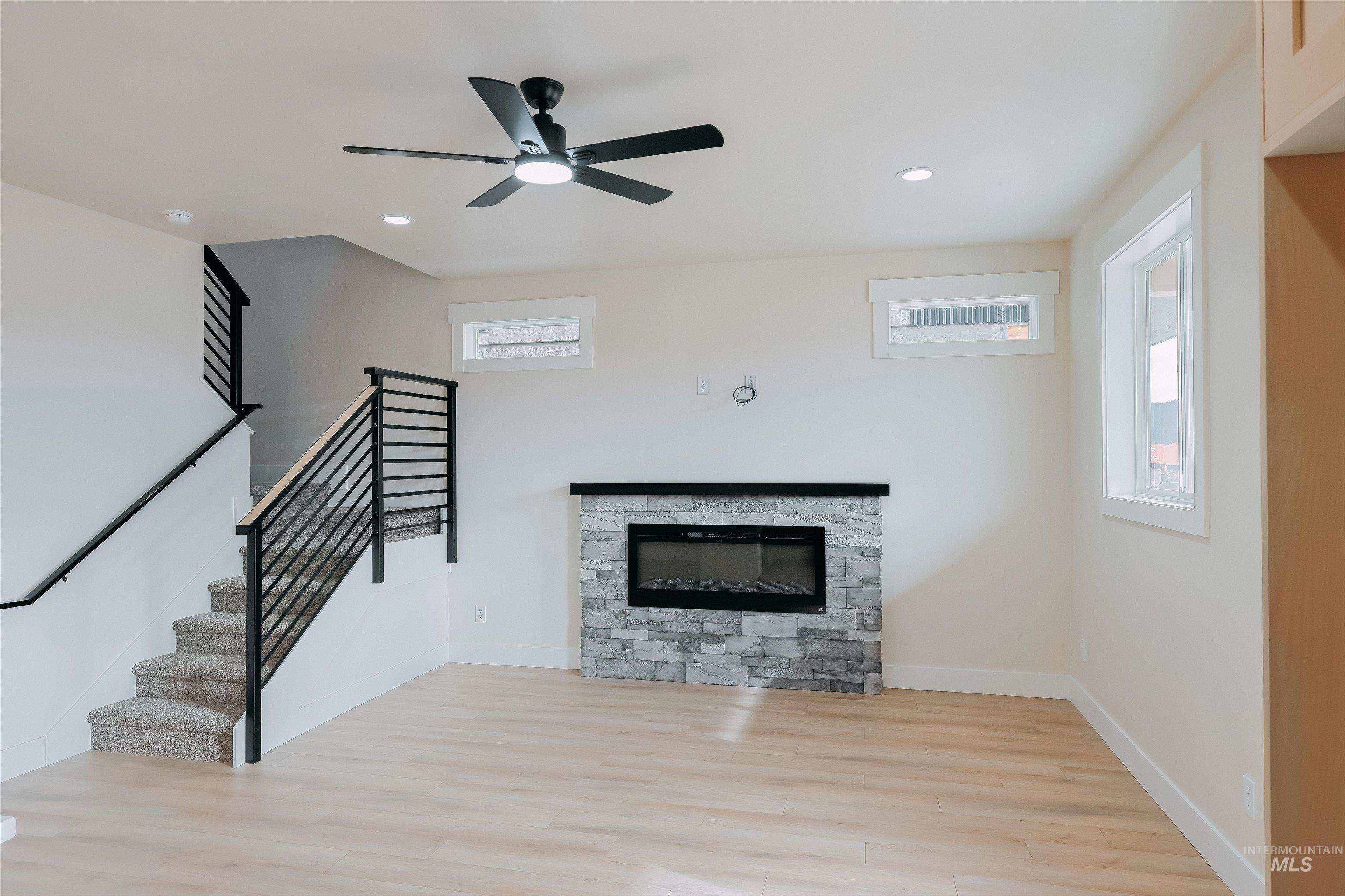 10 North Crk Way Cascade, ID 83611 - Photo 6 of 25 Unfurnished living room featuring light wood-style floors, a stone fireplace, a ceiling fan, and recessed lighting