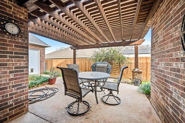 a patio with table and chairs and potted plants