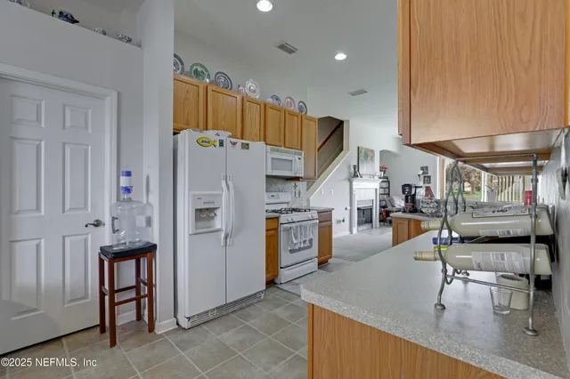 a kitchen with stainless steel appliances kitchen island granite countertop a table chairs and a refrigerator