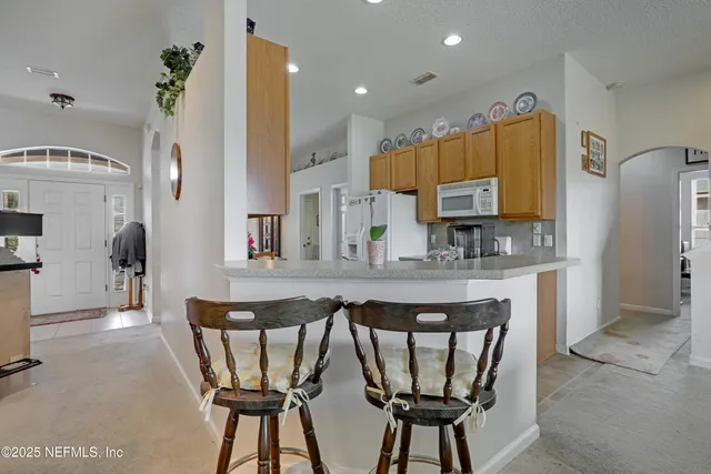a kitchen with stainless steel appliances a dining table chairs and a refrigerator
