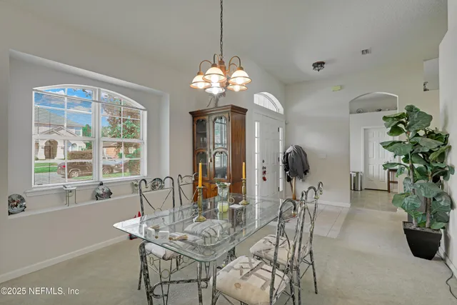 a dining room with furniture potted plants and a chandelier