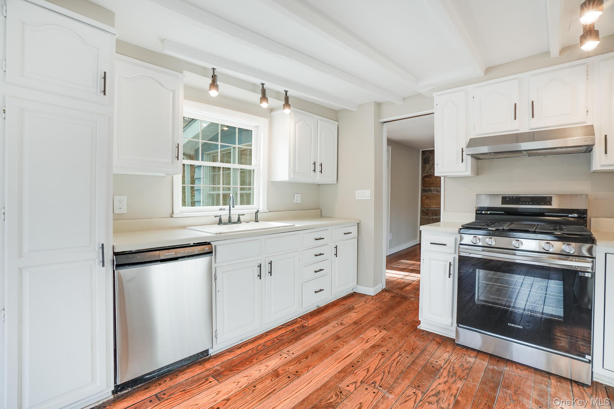 14 Old Rte 55 Pawling, NY 12564 - Photo 9 of 27 Kitchen with appliances with stainless steel finishes, light countertops, under cabinet range hood, white cabinetry, and beamed ceiling