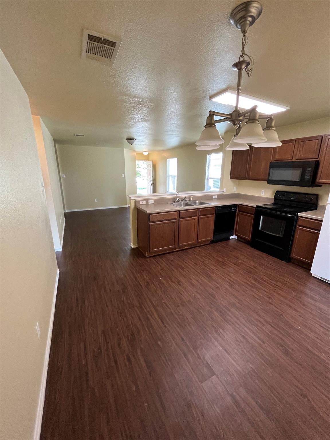 3001 Caleb Drive Austin, TX 78725 - Photo 16 of 16 Kitchen with black appliances, light countertops, dark wood-type flooring, a peninsula, and open floor plan